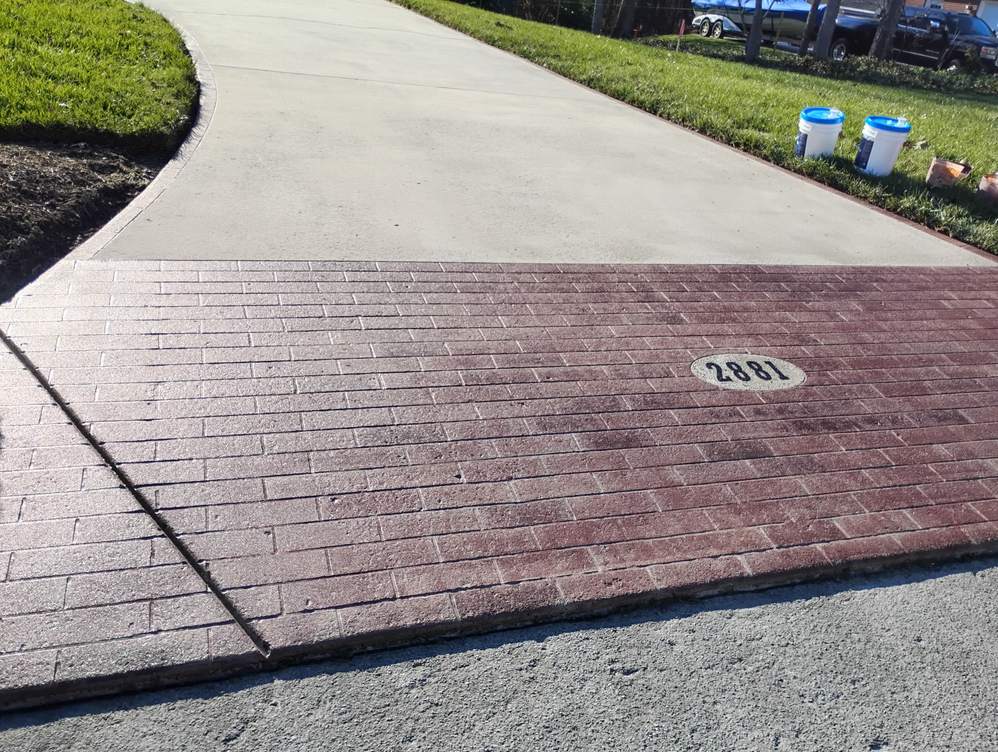 Brick-pattern engraving across a residential concrete driveway apron