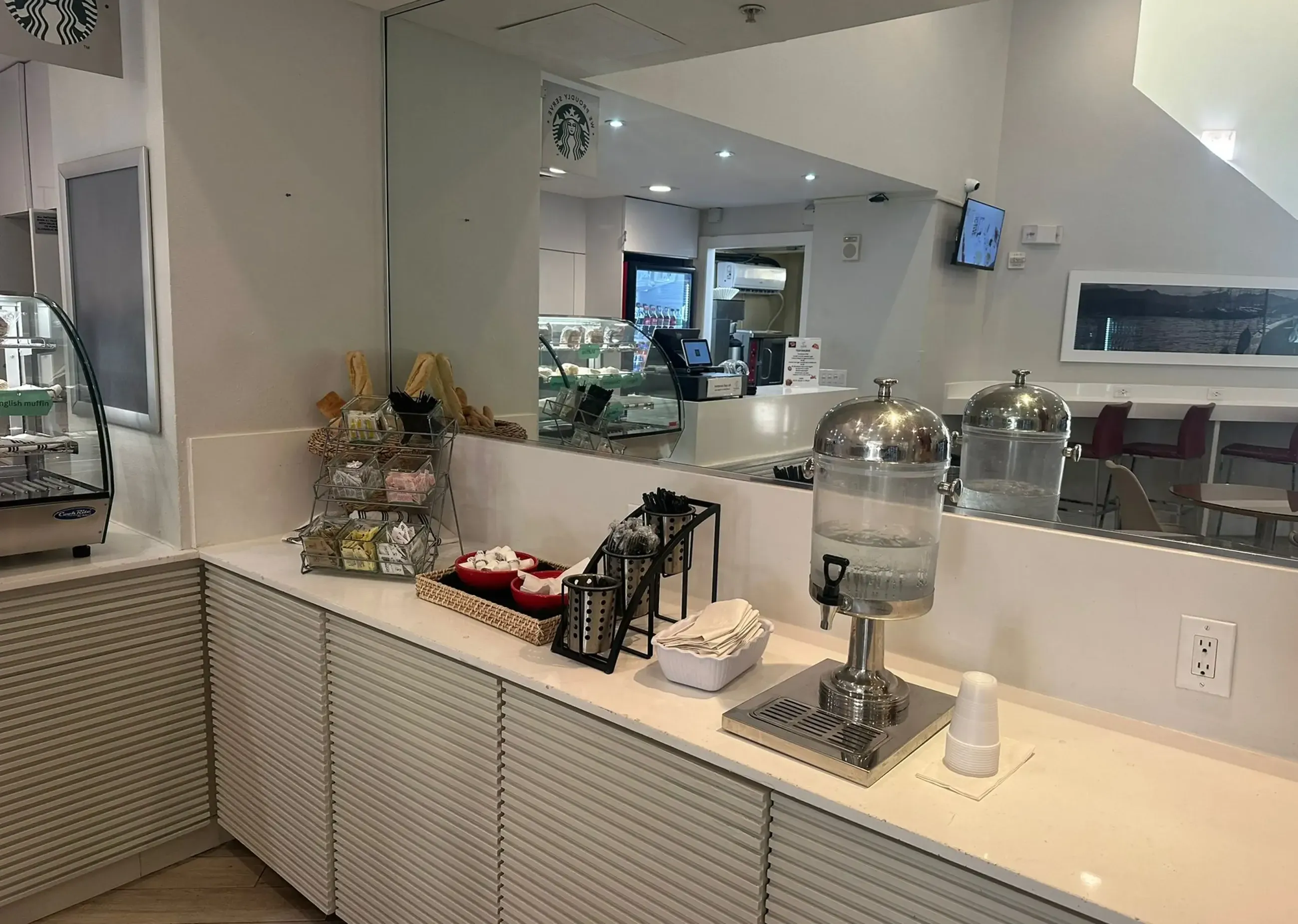 a hotel breakfast buffet counter with a soda machine and pastries