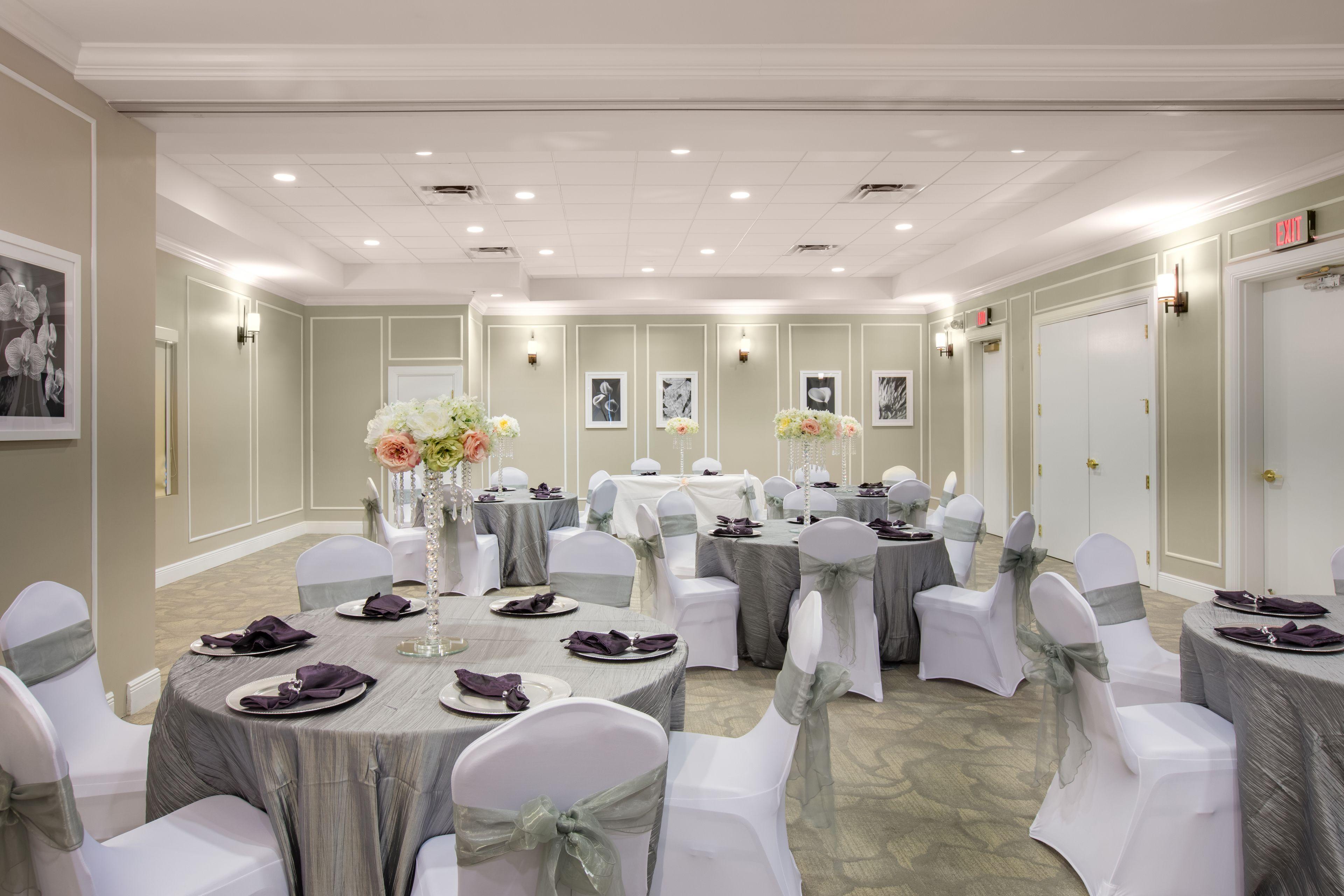 A brightly lit meeting room with round tables set for a formal event.