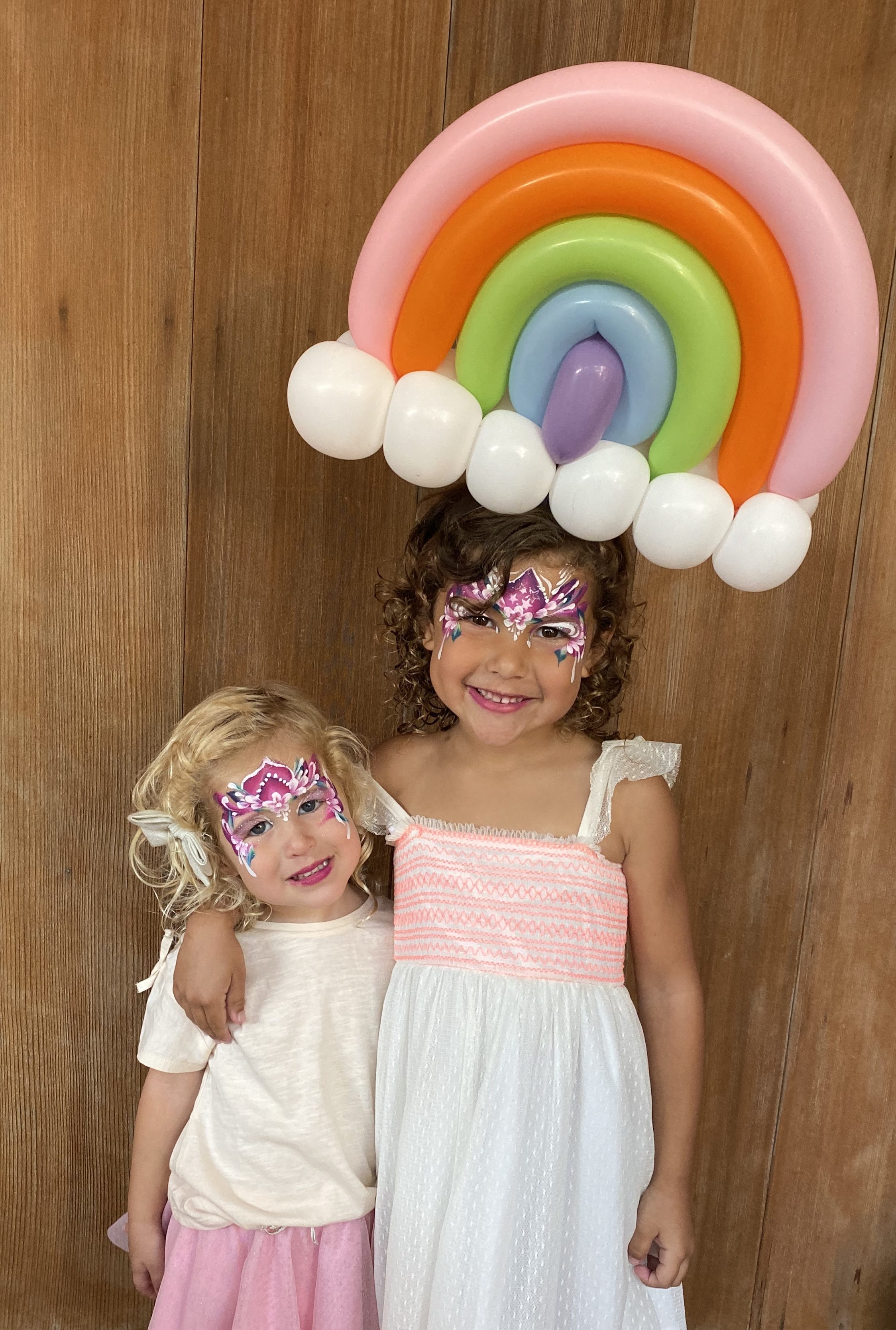 Children enjoying face painting and balloon twisting at a party