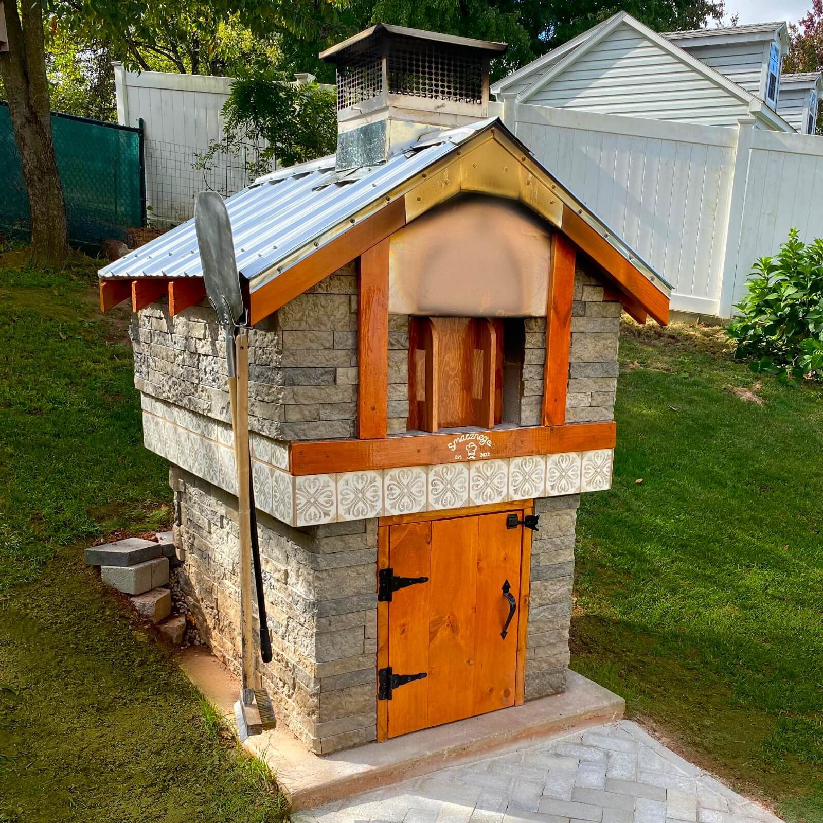 Bethard outdoor pizza oven with a gabled metal roof